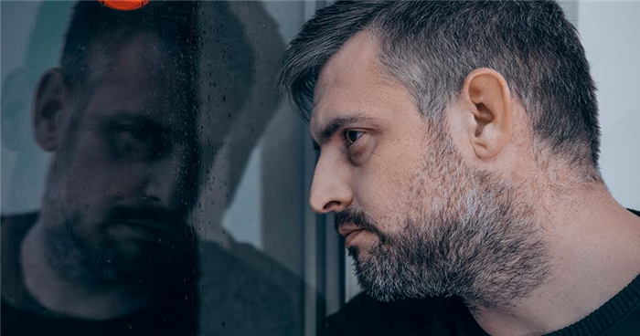 Сумний чоловік дивиться у вікно